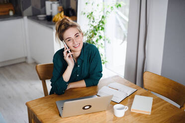 Eine junge Studentin mit Laptop und Smartphone zu Hause, im Home Office und beim Lernen. - HPIF06141
