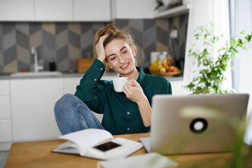 Eine junge Studentin mit Laptop, die Kaffee trinkt, Heimbüro und Lernen. - HPIF06143