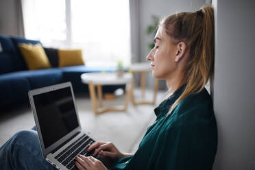 A tired young woman student with laptop at home, home office and learning. - HPIF06153