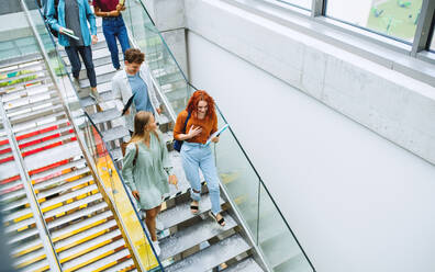 Draufsicht auf Studenten, die im Haus die Treppe hinuntergehen und sich unterhalten. - HPIF06192