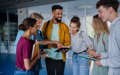 Eine Gruppe fröhlicher Studenten steht in einem Korridor, unterhält sich und lacht. - HPIF06202
