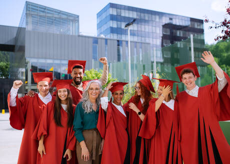 Eine Gruppe fröhlicher Universitätsstudenten mit einem Lehrer, die im Freien feiern und in die Kamera schauen, Abschlusskonzept. - HPIF06240