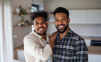 Porträt von jungen erwachsenen Brüdern in der Küche zu Hause, die in die Kamera schauen. - HPIF06263