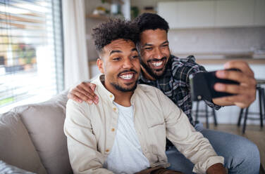 Zwei Brüder fangen einen Moment der brüderlichen Liebe ein, während sie zu Hause auf dem Sofa liegen und ein Selfie knipsen - HPIF06265