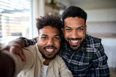 Zwei Brüder halten einen Moment in der Küche fest und lächeln für ein Selfie in ihrem gemütlichen Zuhause - HPIF06266
