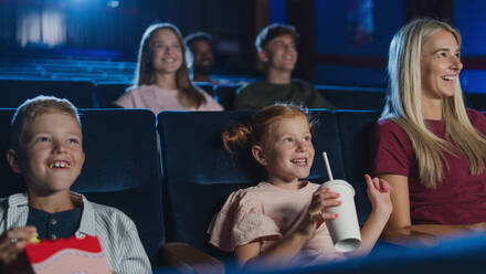 Eine Mutter mit glücklichen kleinen Kindern im Kino, die sich einen Film ansehen. - HPIF06312