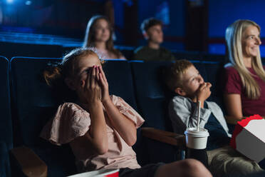 Eine Mutter mit kleinen Kindern im Kino, die einen Film ansehen. - HPIF06316