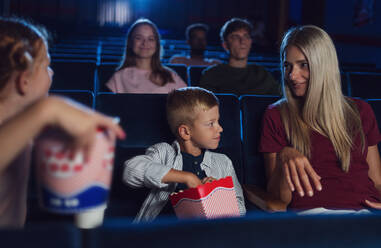 Eine Mutter mit glücklichen kleinen Kindern im Kino, die einen Film ansehen und Popcorn essen. - HPIF06317