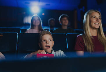 Eine Mutter mit glücklichen kleinen Kindern im Kino, die sich einen Film ansehen. - HPIF06318