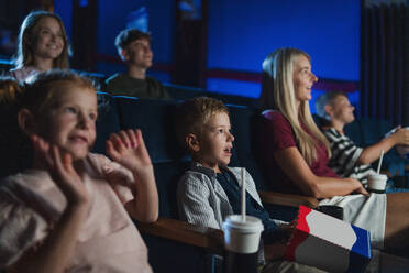 Eine Mutter mit glücklichen kleinen Kindern im Kino, die sich einen Film ansehen. - HPIF06319