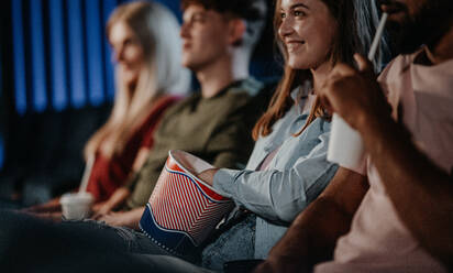 Mittelteil von nicht wiederzuerkennenden, fröhlichen jungen Leuten, die im Kino sitzen und sich einen Film ansehen. - HPIF06330