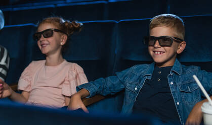 Glückliche kleine Kinder mit 3D-Brille und Popcorn im Kino, die einen Film sehen. - HPIF06332