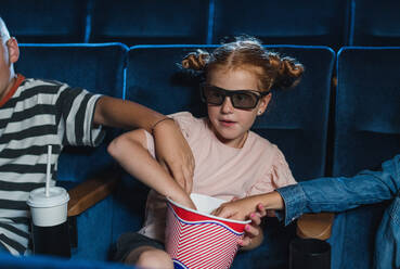Glückliche kleine Kinder mit 3D-Brille und Popcorn im Kino, die einen Film sehen und Popcorn essen. - HPIF06333