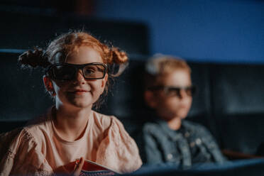 Kleine Kinder mit 3D-Brille und Popcorn im Kino, die sich einen Film ansehen. - HPIF06334