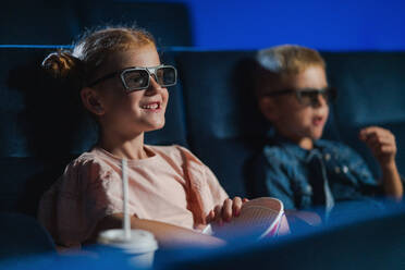 Kleine Kinder mit 3D-Brille und Popcorn im Kino, die sich einen Film ansehen. - HPIF06335