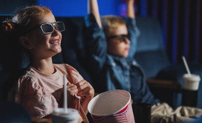 Kleine Kinder mit 3D-Brille und Popcorn im Kino, die sich einen Film ansehen. - HPIF06336