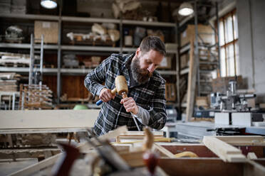 A portrait of mature male carpenter working on his product. Small business concept. - HPIF06387