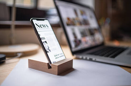 Ein Smartphone im Holzständer auf dem Tisch zu Hause oder im Büro. - HPIF06448