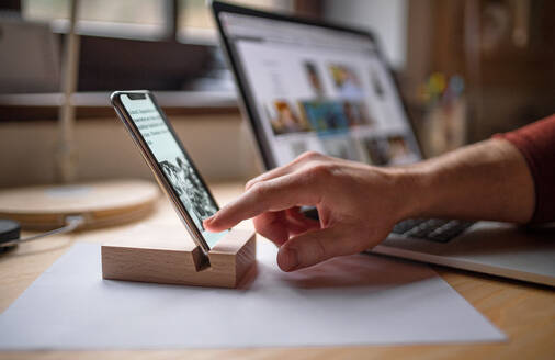 Ein Smartphone im Holzständer auf dem Tisch zu Hause oder im Büro. - HPIF06450