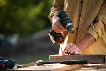 Eine Nahaufnahme von Handwerker Schreiner arbeiten in Schreinerei diy Werkstatt im Freien mit Bohrer. - HPIF06484