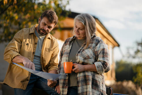 A mature couple having coffee break when working together on construction site of their new house. - HPIF06485