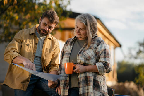 Ein reifes Ehepaar macht Kaffeepause bei der gemeinsamen Arbeit auf der Baustelle ihres neuen Hauses. - HPIF06485