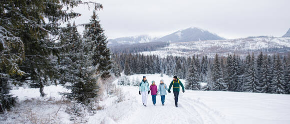 Eine glückliche Familie mit kleinen Töchtern beim Spaziergang in der winterlichen Natur des Tatra-Gebirges in der Slowakei. - HPIF06552