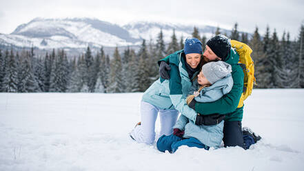 Glückliche Familie mit kleiner Tochter, die sich in der winterlichen Natur der Tatra in der Slowakei umarmt. - HPIF06564