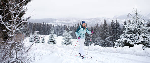 Eine glückliche erwachsene Frau beim Skilanglauf im Freien in der winterlichen Natur des Tatra-Gebirges in der Slowakei. - HPIF06584