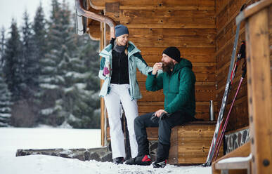 Reifes Paar trinkt heißen Tee bei Holzhütte im Freien im Winter Natur, Skilanglauf. - HPIF06587