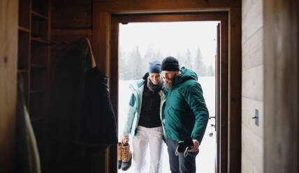 Porträt eines reifen Paares, das eine Holzhütte betritt, Urlaub im Winter, Naturkonzept. - HPIF06594