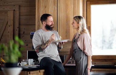 A mature couple having fun when cooking and eating indoors in kitchen. - HPIF06618