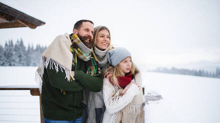 Glückliche Familie mit kleiner Tochter auf Terrasse im Freien, Urlaub in winterlicher Natur. - HPIF06620