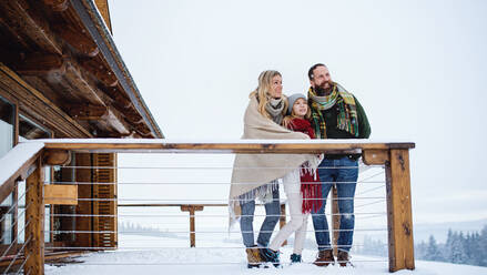 Glückliche Familie mit kleiner Tochter auf Terrasse im Freien, Urlaub in winterlicher Natur. - HPIF06621