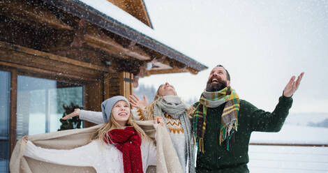 Glückliche Familie mit kleiner Tochter, die sich auf der Terrasse im Freien amüsiert, Urlaub in der winterlichen Natur. - HPIF06622