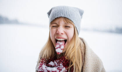 Headshot von glücklichen preteen Mädchen tun Grimasse und Sticking Zunge heraus mit Schnee im Freien im Winter Natur - HPIF06628