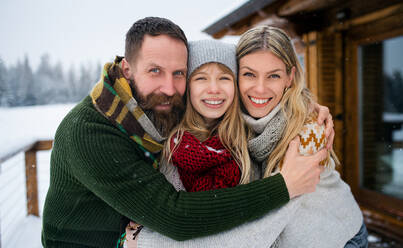 Porträt einer Familie mit kleiner Tochter im Freien im Winterferienhaus, Blick in die Kamera. - HPIF06634