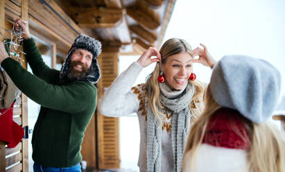 Happy family with small daughter decorating terrace of house outdoors in winter, Christmas time. - HPIF06637