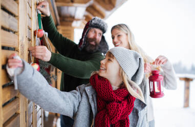 Happy family with small daughter decorating terrace of house outdoors in winter, Christmas time. - HPIF06641