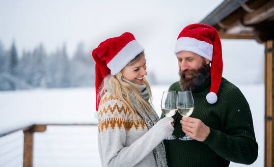 Glückliches reifes Paar trinkt Wein auf der Terrasse im Freien im Winter Natur, Urlaub zur Weihnachtszeit. - HPIF06645