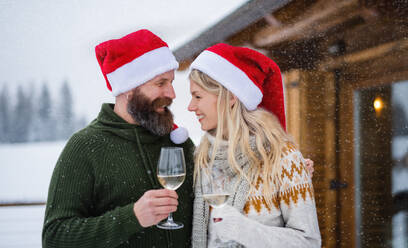 Glückliches reifes Paar trinkt Wein auf der Terrasse im Freien im Winter Natur, Urlaub zur Weihnachtszeit. - HPIF06646
