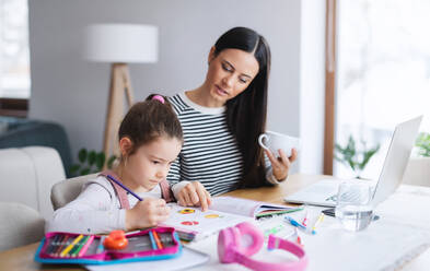 Mother with school girl indoors at home, distance learning and home office concept. - HPIF06648