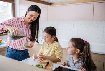 Mutter mit Mädchen zu Hause bei der Zubereitung eines gesunden Fruchtsmoothie. - HPIF06664