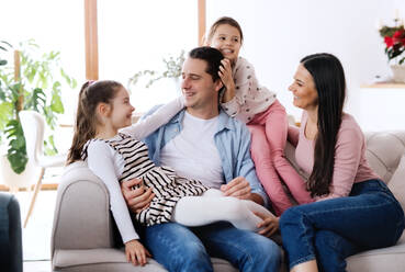 Portrait of parents with small daughters sitting on sofa indoors at home, relaxing. - HPIF06671