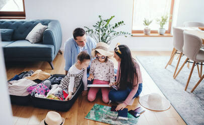 Glückliche vierköpfige Familie fängt Erinnerungen ein, während sie für den Sommerurlaub zu Hause packt - HPIF06678