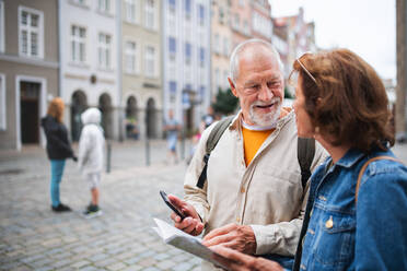 Ein Porträt von glücklichen älteren Paar Touristen mit Karte und Smartphone im Freien in der Stadt Straße - HPIF06694