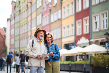 Ein Porträt von glücklichen älteren Paar Touristen mit Karte und Smartphone im Freien in der Stadt Straße - HPIF06699