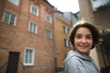 A portrait of happy preteen girl turning round and looking at camera outdoors in street. - HPIF06717