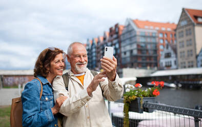 Ein fröhliches älteres Ehepaar macht ein Selfie inmitten des historischen Charmes der Stadt während ihrer touristischen Entdeckungsreise - HPIF06723