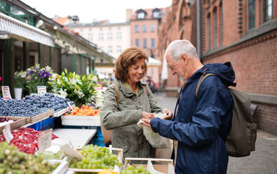 Ein glückliches älteres Touristenpaar kauft auf dem Markt in der Stadt Obst. - HPIF06737